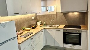 A compact kitchen with white cabinets, a built-in oven, and a sink.