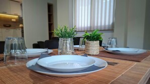 A dining table set with plates, cutlery, and two small potted plants in woven containers.