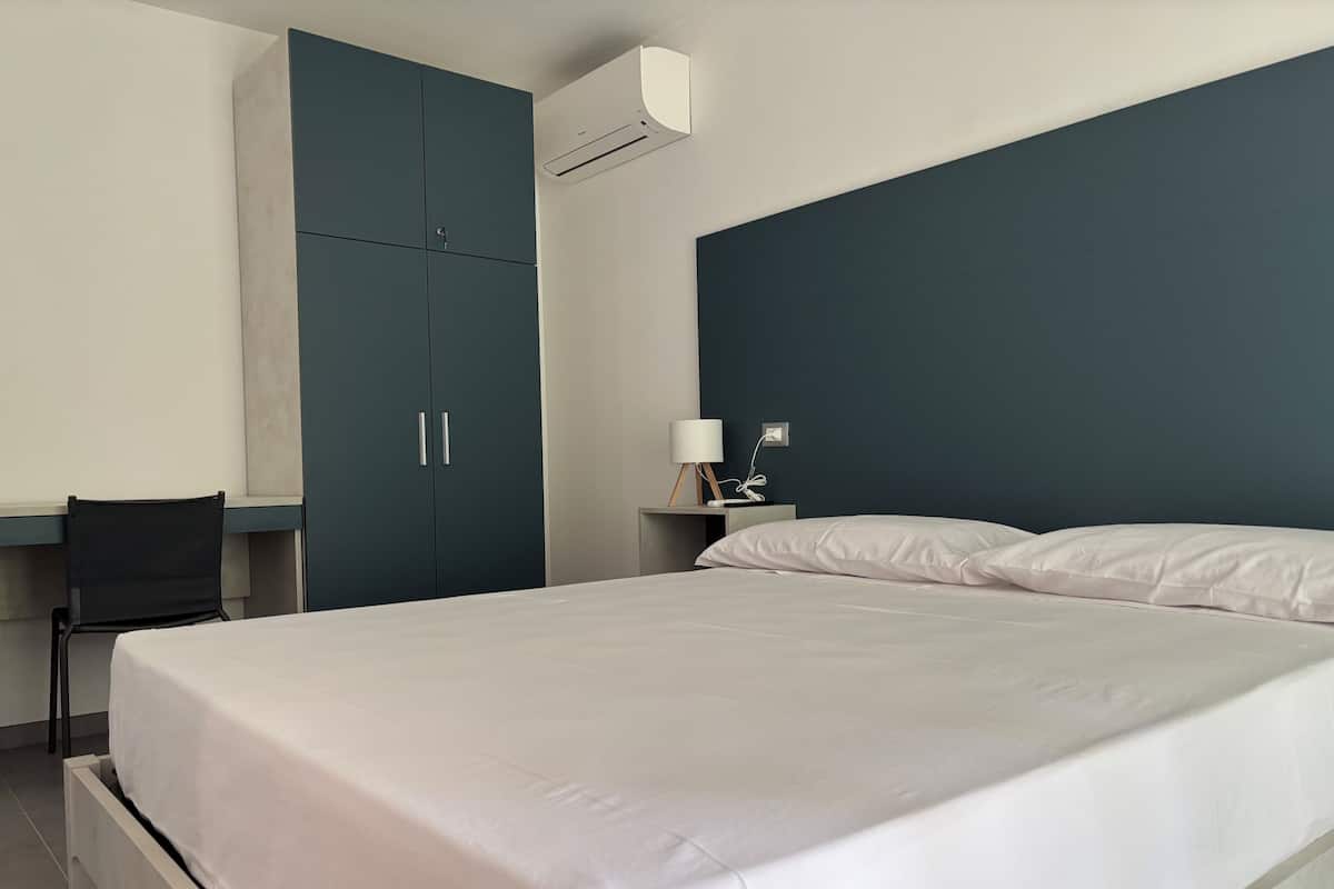 A hotel room with a bed, a desk, and a wardrobe.