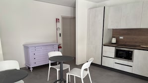 Ett modernt kök med vita skåp, en inbyggd ugn och en kaffebryggare på bänkskivan.