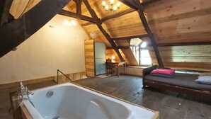 A wooden cabin with a large bathtub, a bed, and a dining area. - Small, quiet country house, 100% nature, no neighbors or noise (Tinchebray-Bocage)
