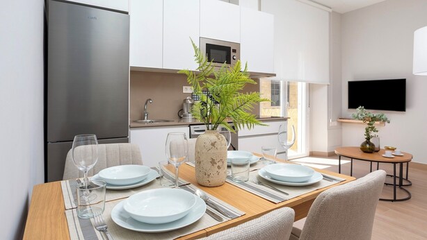 Una cocina moderna con armarios blancos, un refrigerador de acero inoxidable y un microondas.