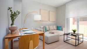 Een moderne woonkamer met een eethoek, een bank, een salontafel en een potplant.