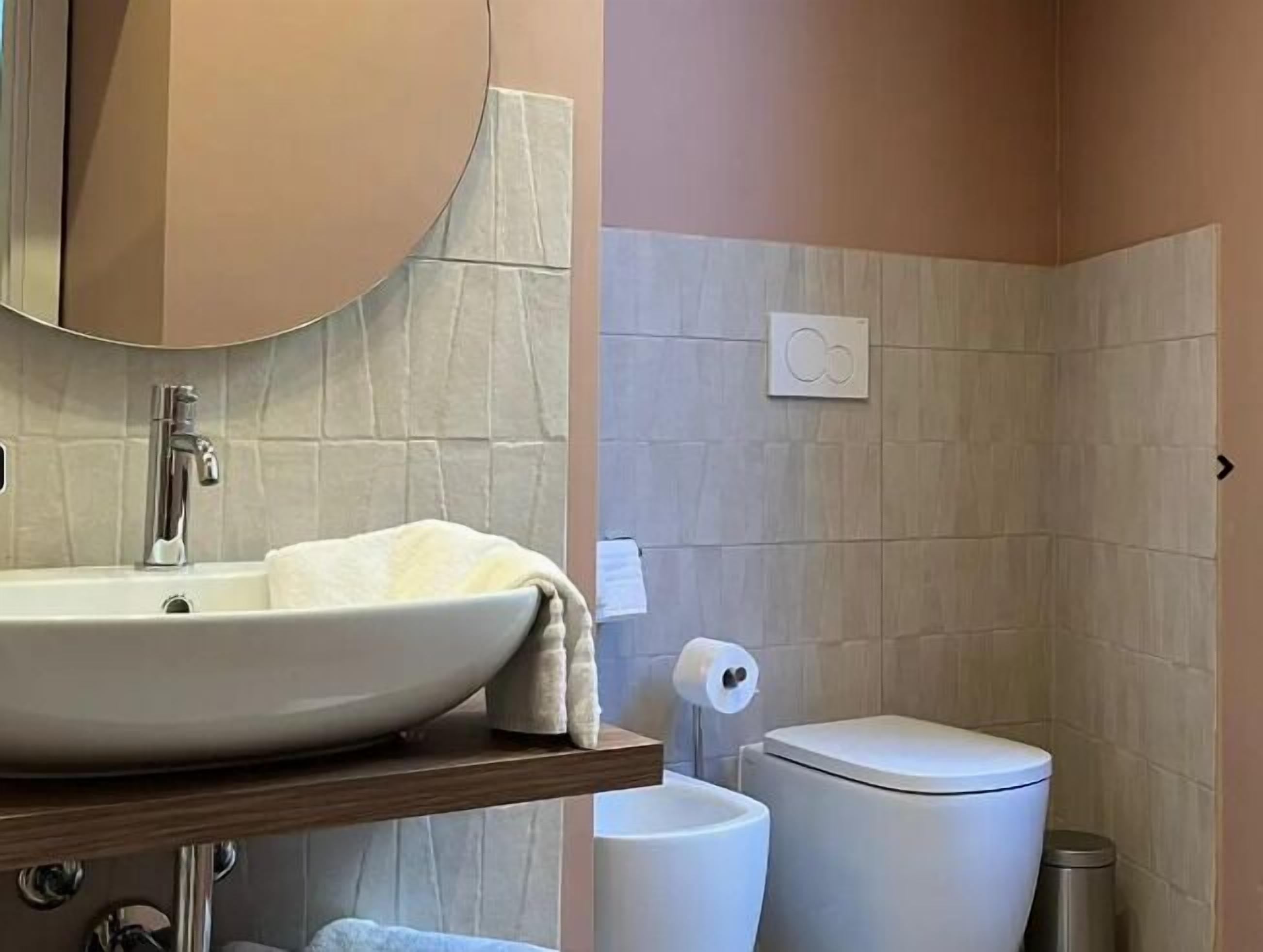 Ein Badezimmer mit einem weißen Waschbecken, einer Toilette und einem Spiegel.
