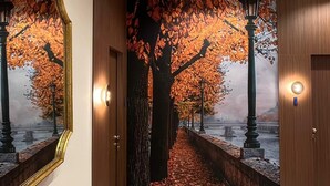 A hallway with a wooden bench, a mirror, and a wall mural of a tree-lined pathway. - Natorè Camere di Charme (Verona)