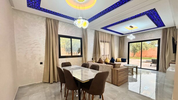 A spacious living area with a dining table, sofas, and a large window. - Villa with pool Aghmat (Marrakesh)