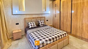 A bedroom with a bed, bedside tables, a wardrobe, and built-in lighting. - Villa with pool Aghmat (Marrakesh)