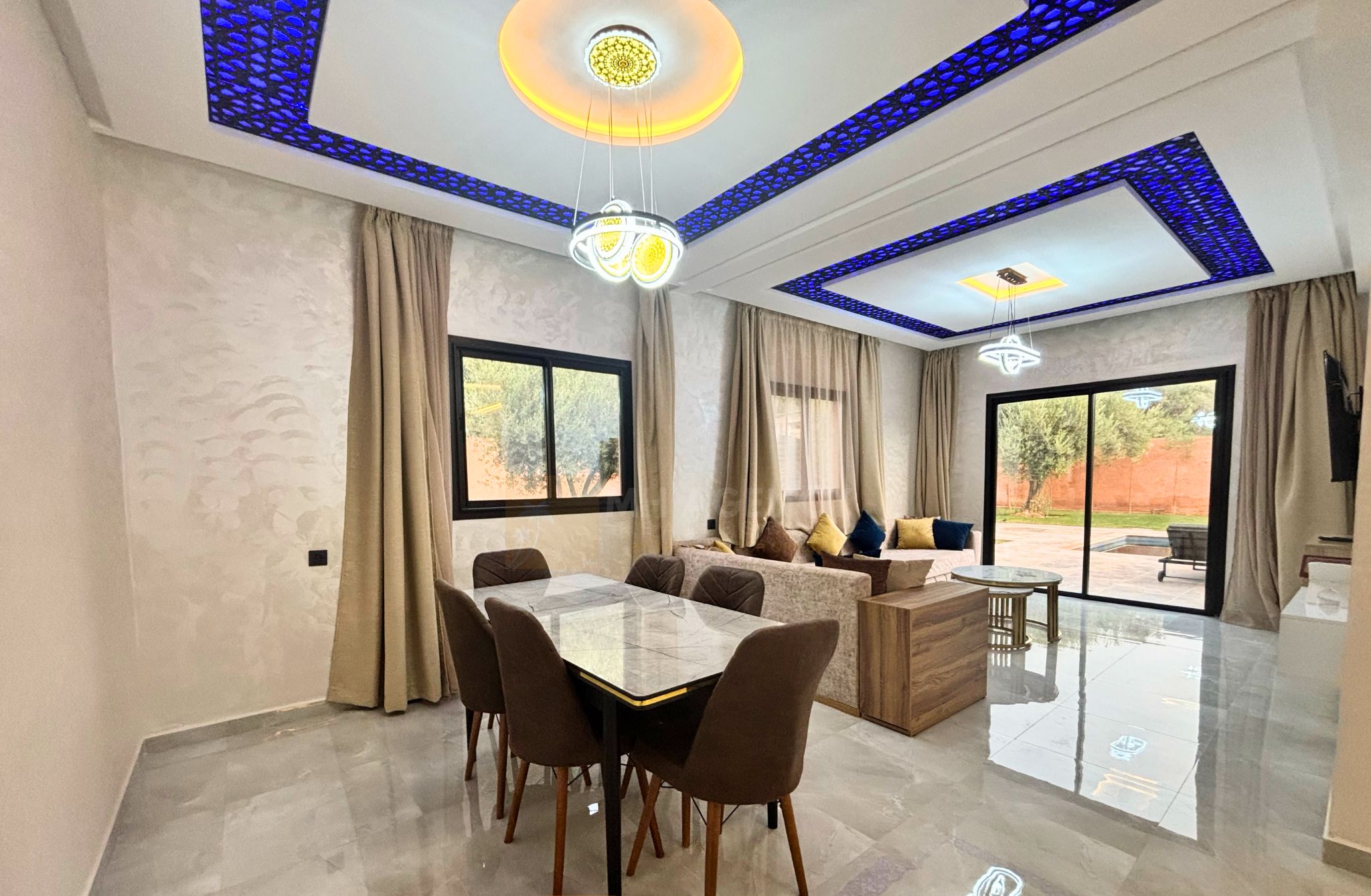 A spacious living area with a dining table, sofas, and a large window.