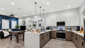 A modern kitchen with a central island, stainless steel appliances, and a dining area with a foosball table.