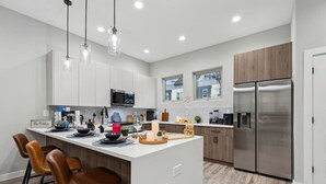 A modern kitchen with a central island, stainless steel appliances, and pendant lighting.