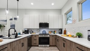 A modern kitchen with white cabinets, a stainless steel oven, and a herringbone-patterned backsplash.