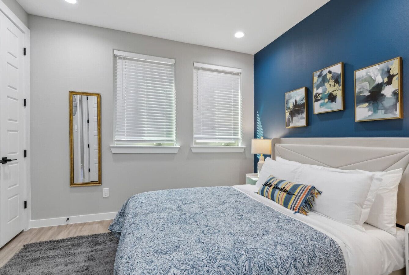 A bedroom with a bed, bedside table, lamp, and artwork on the wall.