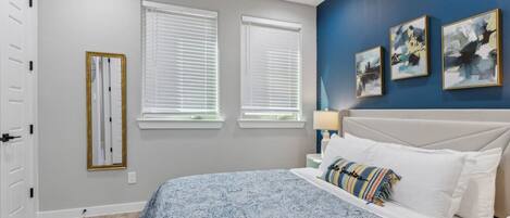 A bedroom with a bed, bedside table, lamp, and artwork on the wall.