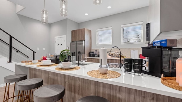 A modern kitchen with a central island, bar stools, and a coffee station. - The Jasper 2BD TH: 7ST Walkable, Stylish & Homey! (Fort Worth)