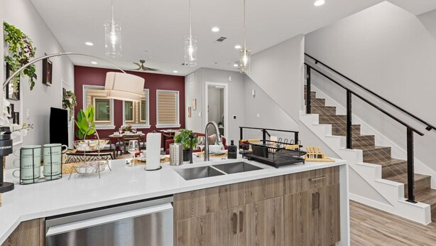 A modern kitchen with a central island, stainless steel appliances, and a staircase leading to an upper level. - The Quartz 2BD TH: 7ST Walkable, JOYfull & Comfy! (Fort Worth)