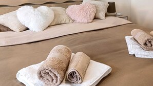 Hotelkamer met een bed, kussens, een hoofdbord, een wandlamp en een schilderij van een toekan en bloemen.