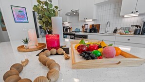 A kitchen counter with a fruit tray, candles, and a decorative plant.