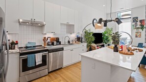 A modern kitchen with white cabinetry, stainless steel appliances, and a central island.