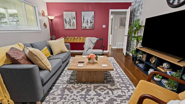 A living room with a grey sofa, a wooden coffee table, a patterned rug, and a television on a wooden stand. - Charming 2BD: TCU Walkable, Blissful & Joyful ! (Fort Worth)