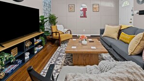 A living room with a TV, sofa, coffee table, and a bookshelf. - Charming 2BD: TCU Walkable, Blissful & Joyful ! (Fort Worth)