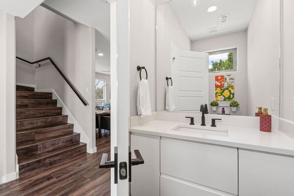 A modern kitchen with white cabinets, a white countertop, and a stainless steel sink.