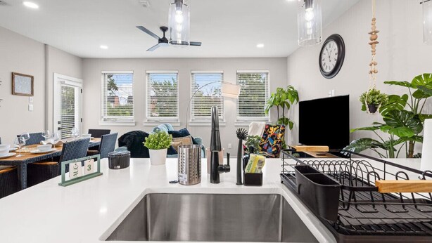Een moderne keuken met een centraal eiland, een eetgedeelte met een tafel voor vier personen, en een zithoek met een bank en stoelen.