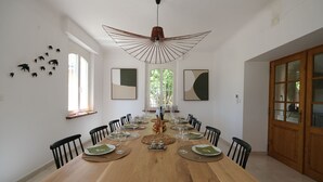 A dining room with a long wooden table set for a meal, surrounded by chairs, with a unique ceiling light fixture above. - Villa air-conditioning heated swimming pool Alpilles view Mouries (Mouriès)
