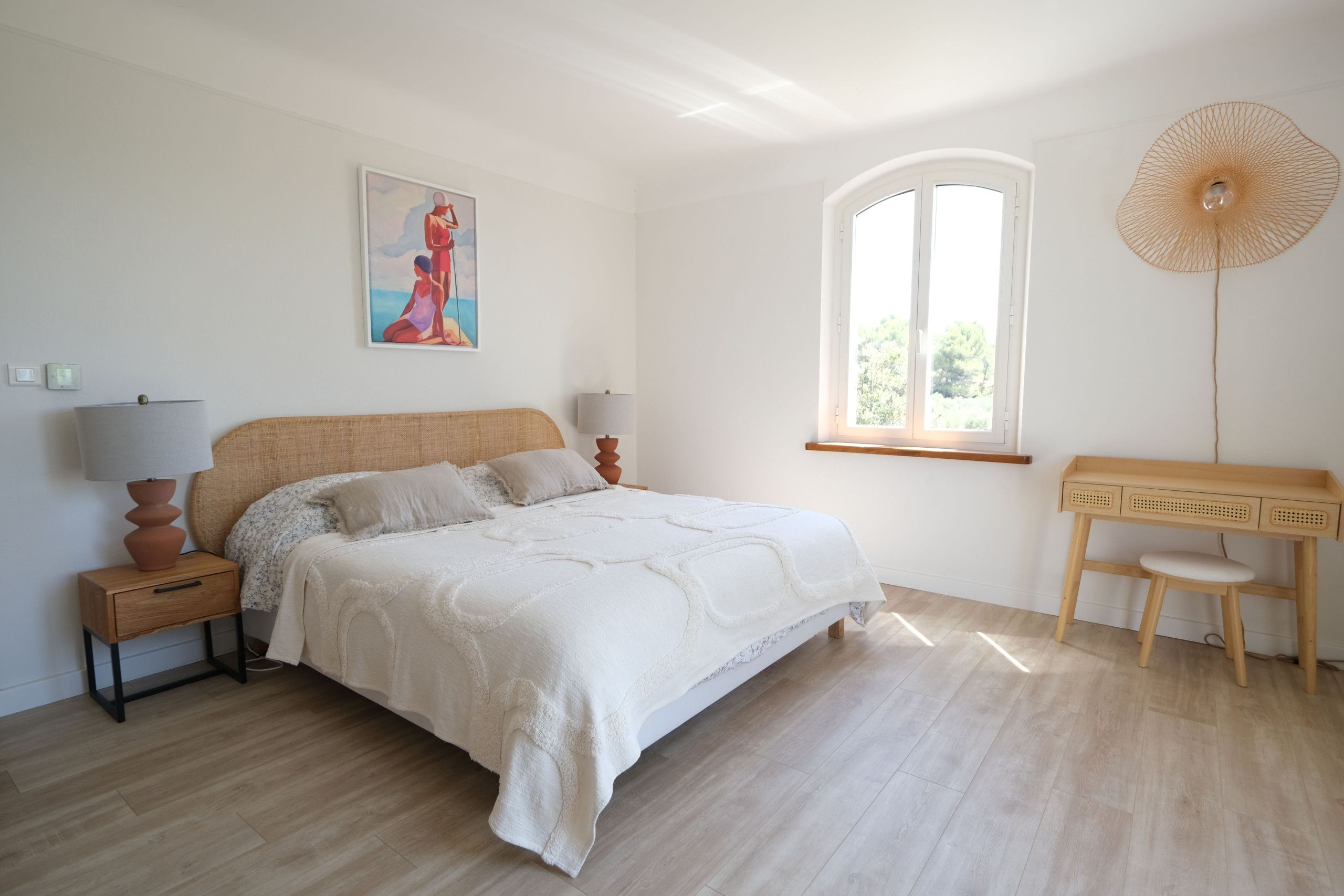 Ein Schlafzimmer mit einem Bett, Nachttischen, einem Schreibtisch und einem Fenster.