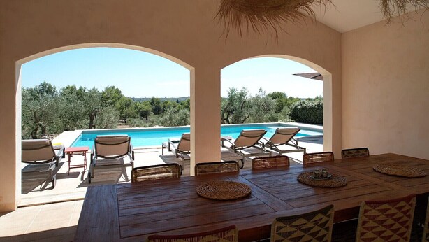 A poolside dining area with a view of a pool and trees. - Villa air-conditioning heated swimming pool Alpilles view Mouries (Mouriès)