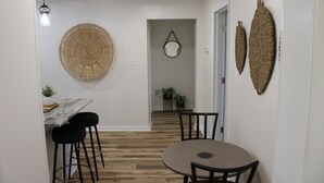 A dining area with a round table and four chairs, a hanging light fixture, and two wall-mounted woven decorations. - Delightful 2-bedroom house with AC in charming Easley (Easley)