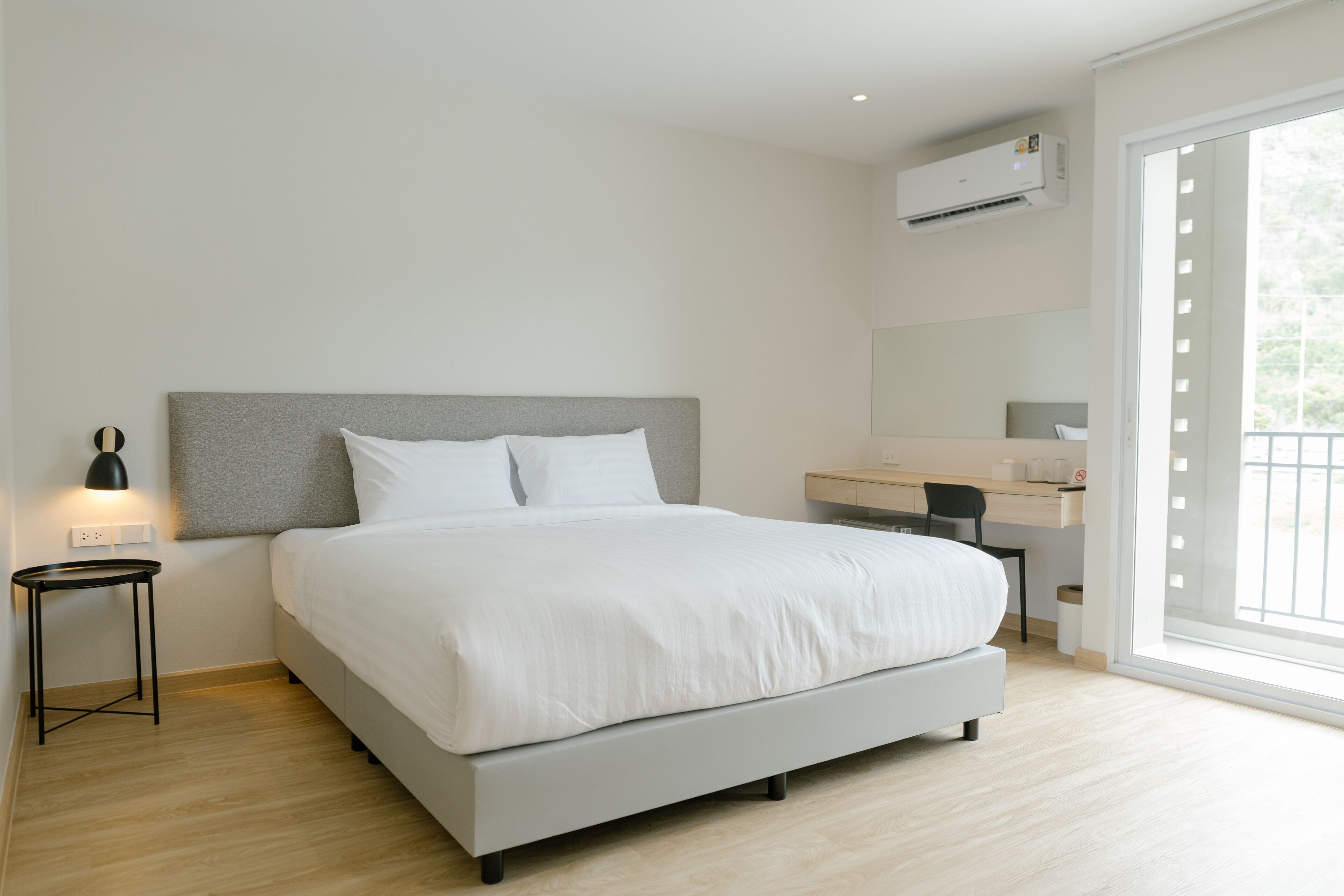A modern bedroom with a bed, bedside table, and a desk with a chair.