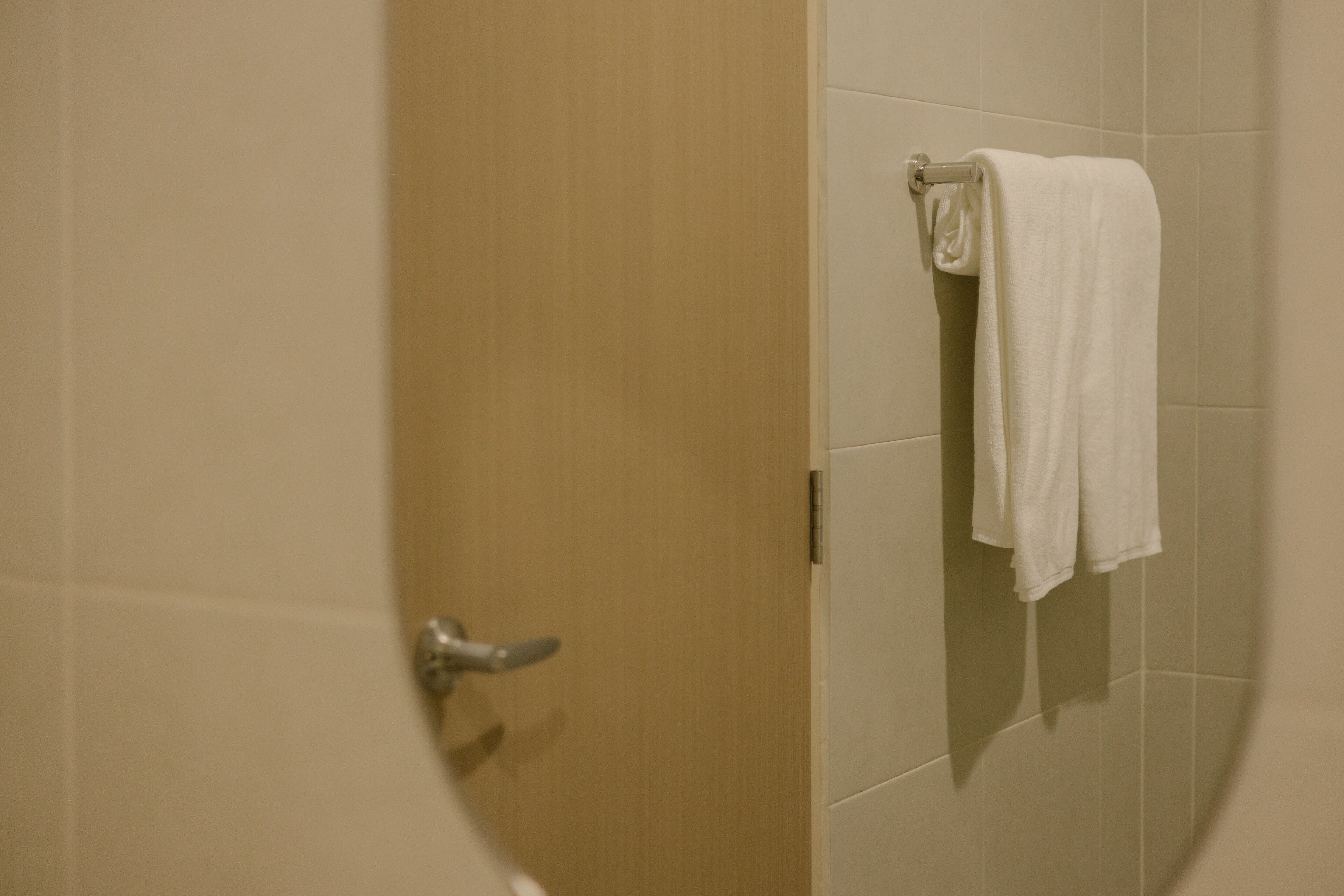 Une salle de bain avec une porte en bois et une serviette blanche suspendue à un porte-serviettes.