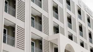 Ein mehrstöckiges Hotel mit Balkonen, Rundbogenfenstern und einer rasterartigen Fassade.