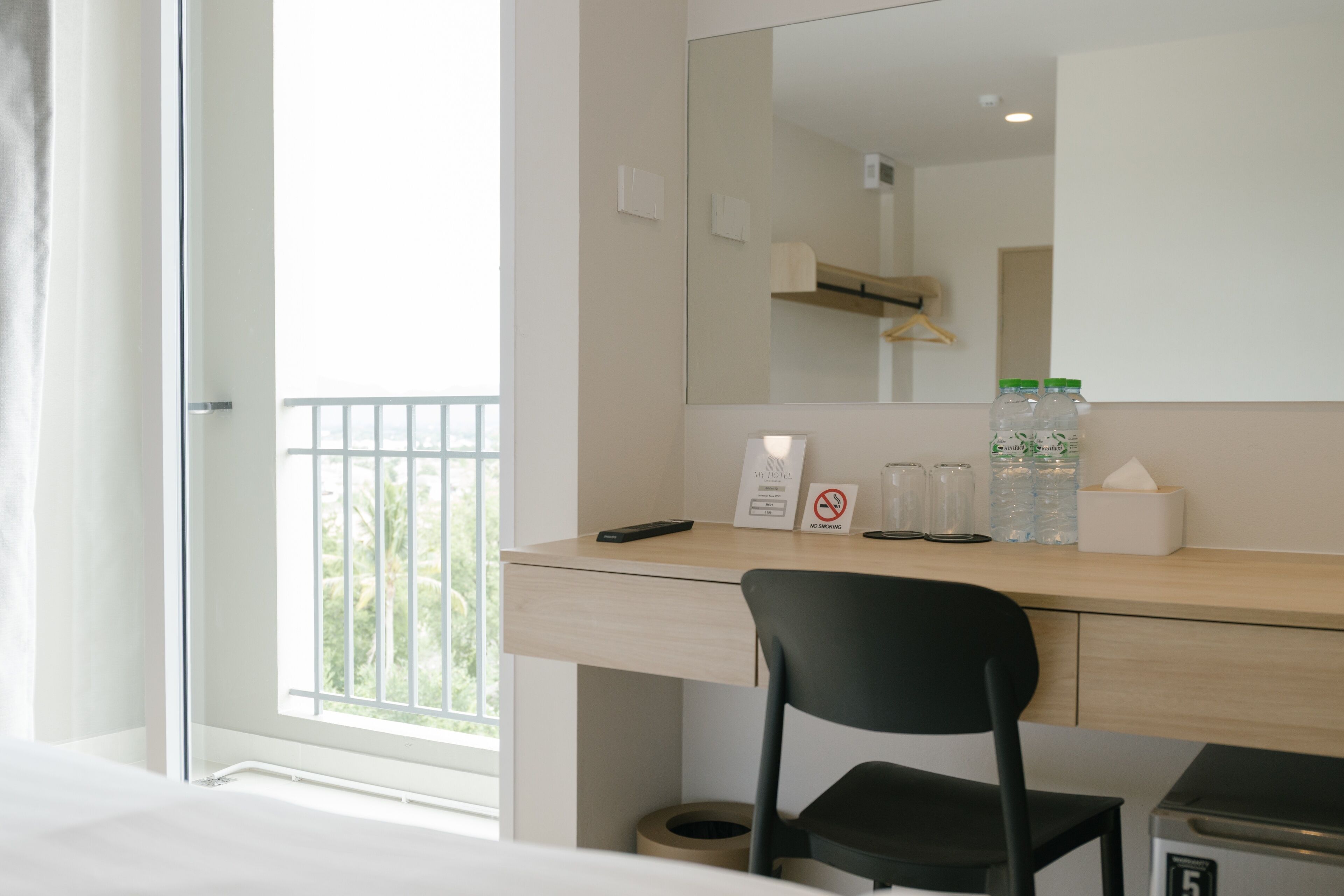 A hotel room with a desk, chair, and a large window.