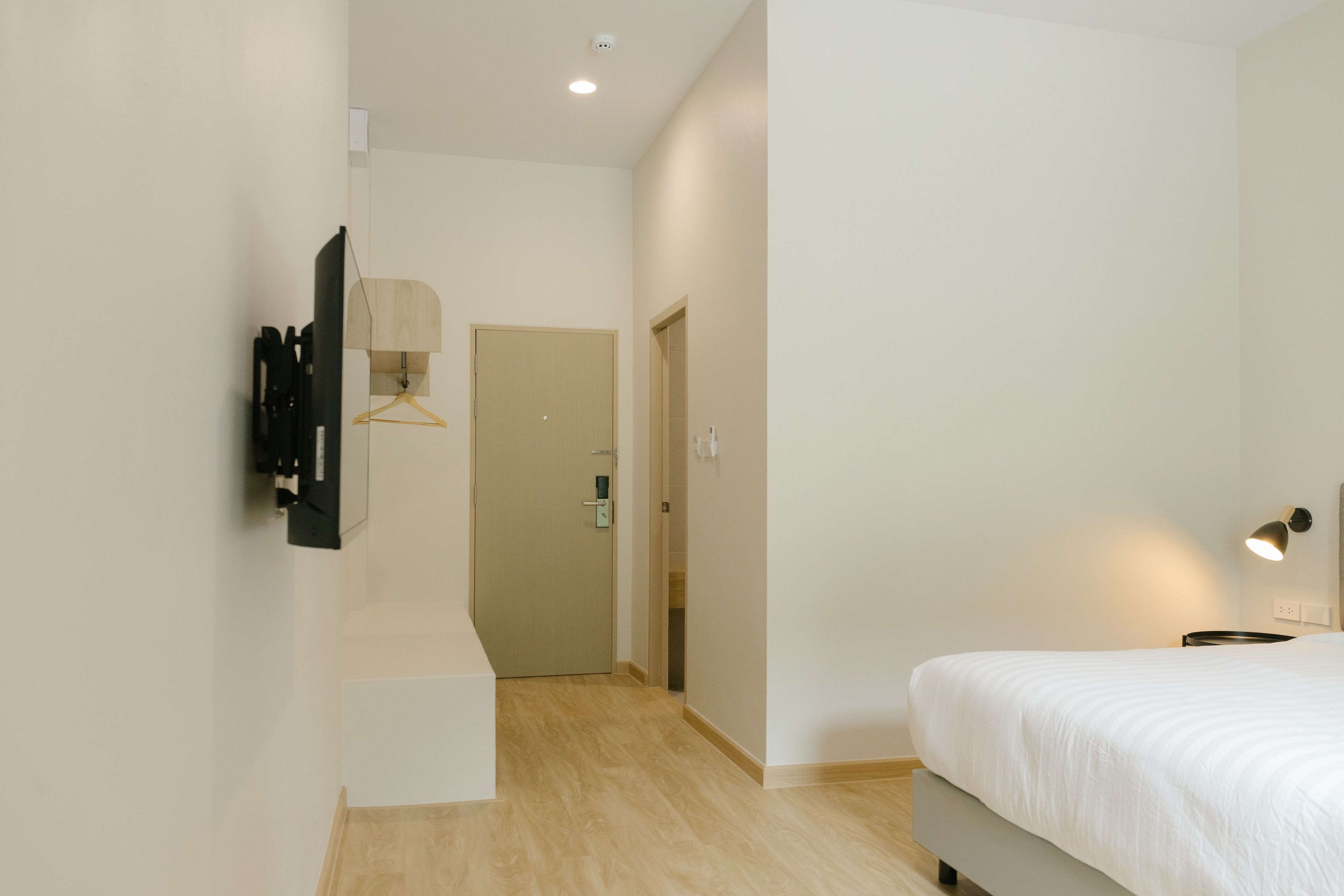 A bedroom with a bed, a hanging light, and a door leading to another room.