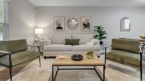 A modern living room with a sofa, two armchairs, a coffee table, and decorative wall art.