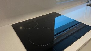 A black induction cooktop with a digital control panel on a white countertop. - Up Sal Business (Aveiro)