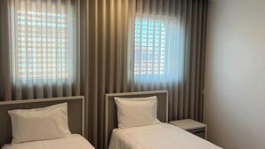 A hotel room with two beds, a nightstand, and a window with curtains. - Up Sal Business (Aveiro)