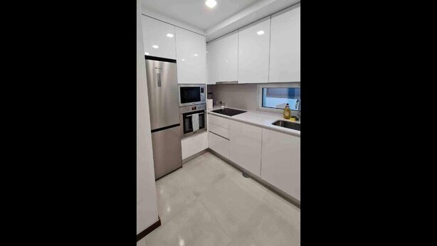 A modern kitchen with white cabinets, stainless steel appliances, and a window above the sink. - Up Sal Business (Aveiro)