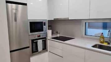 A modern kitchen with white cabinets, stainless steel appliances, and a window above the sink.