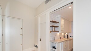 A modern kitchen with white cabinetry, a countertop, and built-in shelves. - Bright and Spacious Studio, Knightsbridge, London - Pass the Keys (London)