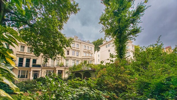 A courtyard with lush greenery, a gazebo, and classical architecture of buildings with multiple stories and balconies. - Bright and Spacious Studio, Knightsbridge, London - Pass the Keys (London)