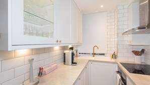 A modern kitchen with white cabinetry, a built-in oven, a coffee machine, and a window with a view of the city. - Bright and Spacious Studio, Knightsbridge, London - Pass the Keys (London)
