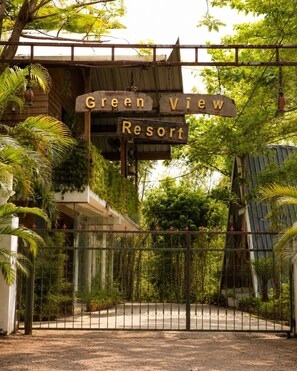 Une entrée fermée par un portail mène au complexe Green View Resort, et une enseigne est placée au-dessus du portail.