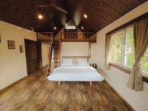 A bedroom with a wooden ceiling, a bed, a wooden ladder, and a window with curtains. - Green View Resort (Karjat)