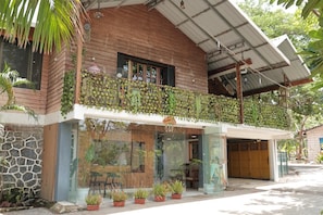 A two-story building with a balcony covered in plants, a stone wall, and a glass entrance. - Green View Resort (Karjat)