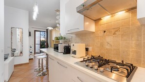 A modern kitchen with a gas stove, white cabinets, and a large island with stools.
