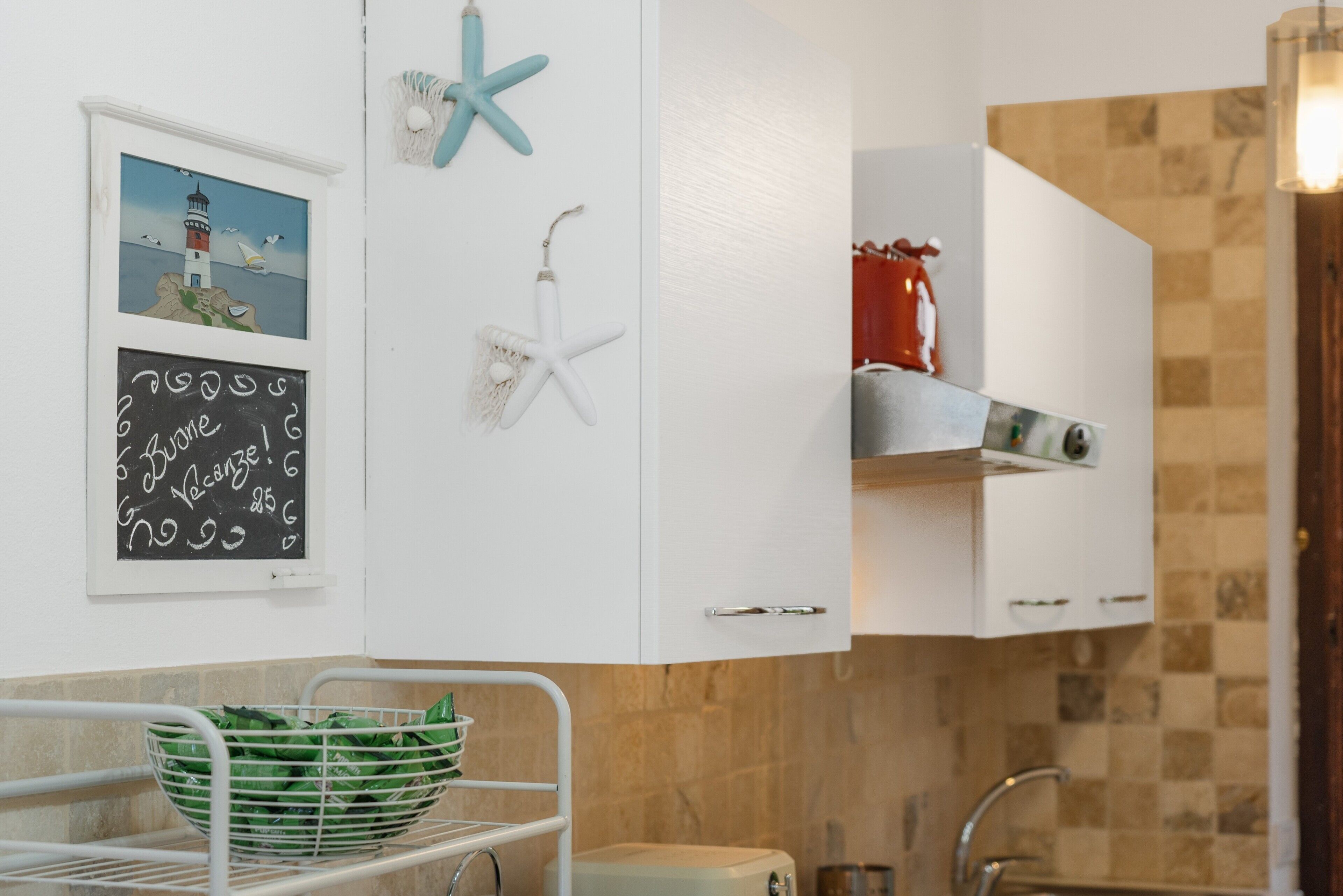 A kitchen with white cabinets, a white sink, and a red appliance on the countertop.