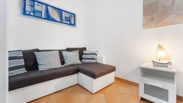 Ein modernes Wohnzimmer mit einer Eckcouch, einem Beistelltisch mit Lampe und einem Wandbild.