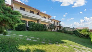 A two-story building with a balcony, surrounded by a well-maintained lawn and stone pathways.